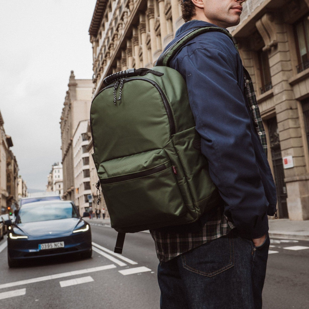 Green backpack with front panel pocket, chain zipper pulls, and shoulder straps.