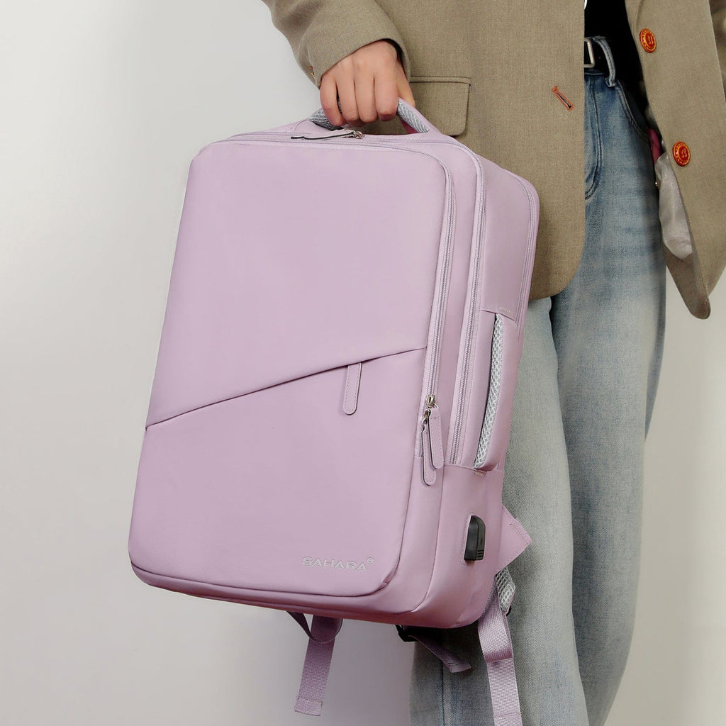 Purple travel backpack held by a person, showing front zip pocket and logo patch