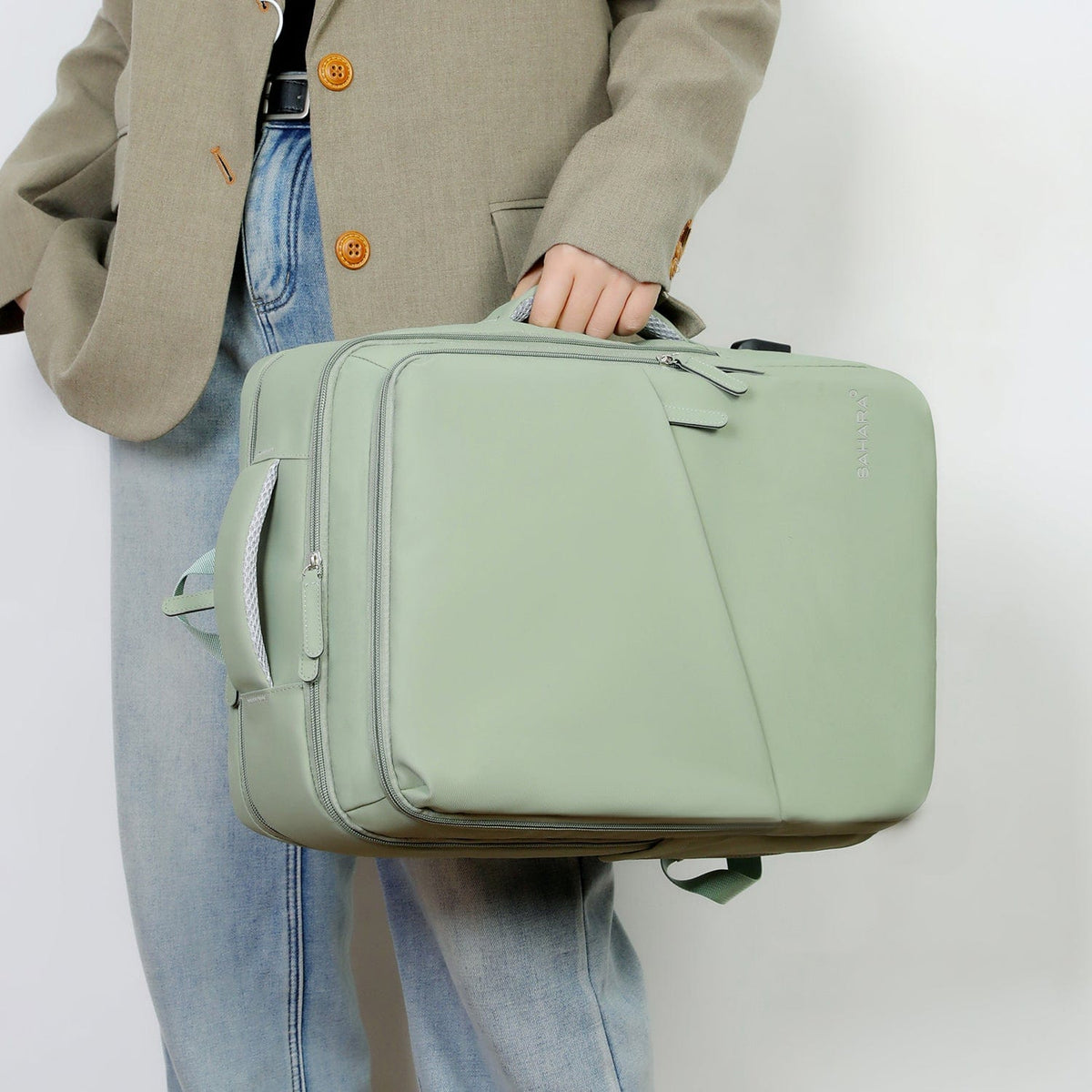 Mint green zip travel backpack held by the handle with front pockets.