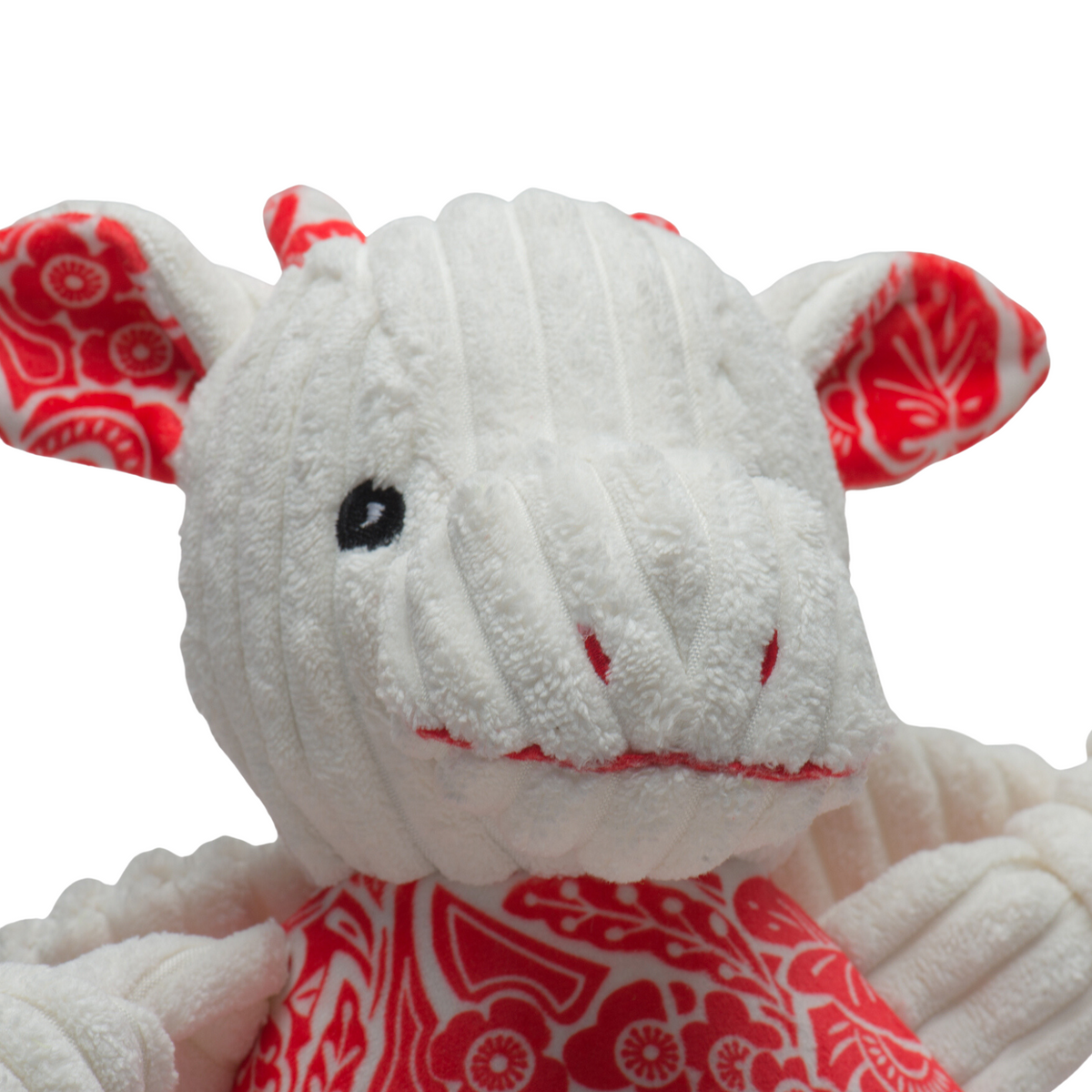 Close-up plush dog toy face with white fur, red patterned dress, and stitched smile