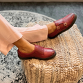 Women’s dark red slip-on shoes with two buckle straps, worn with light pants