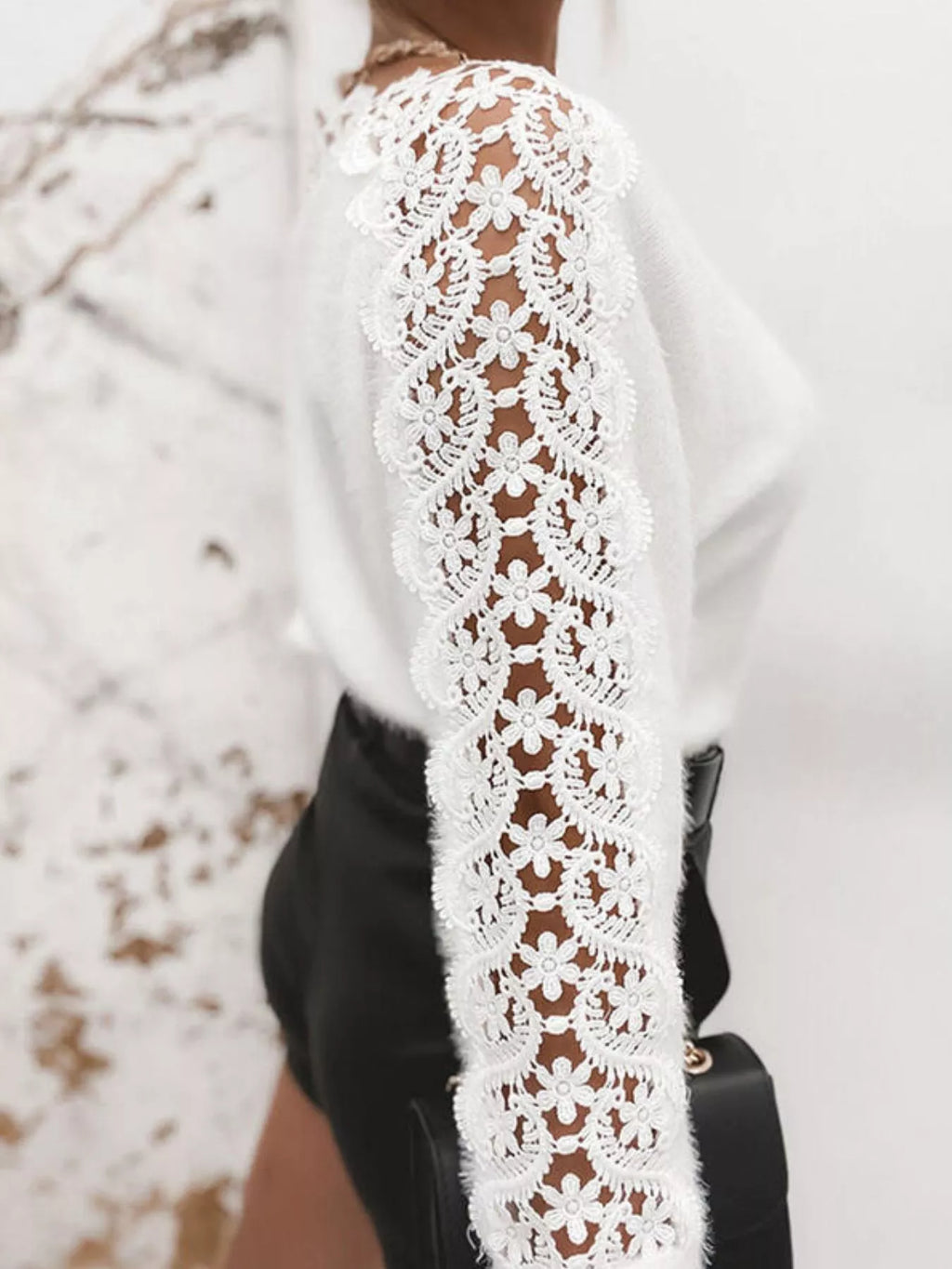 White long-sleeve sweater featuring lace crochet sleeves with floral cutouts