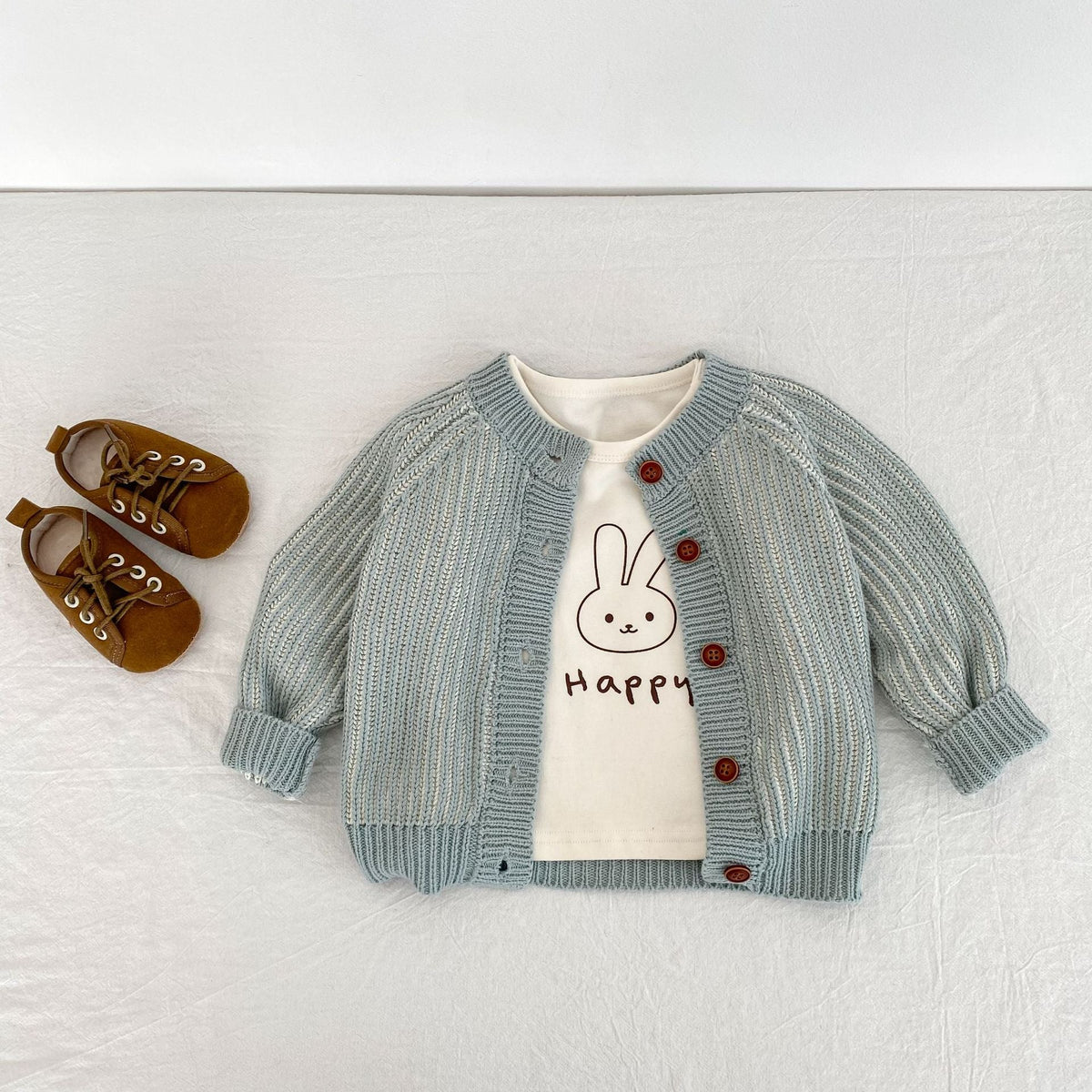 Infant light blue knitted coat with red buttons, round neck; bunny graphic shirt peeks