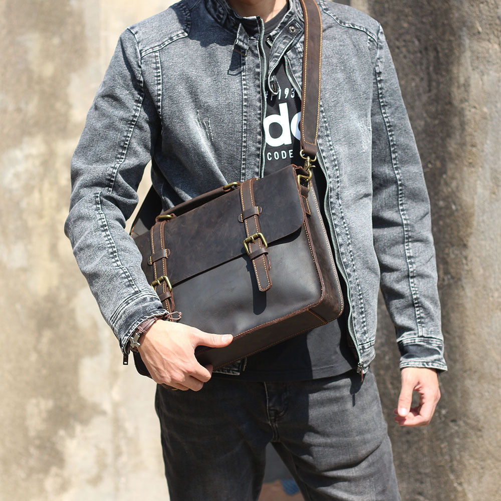 Brown leather messenger bag carried on shoulder with two front buckle straps