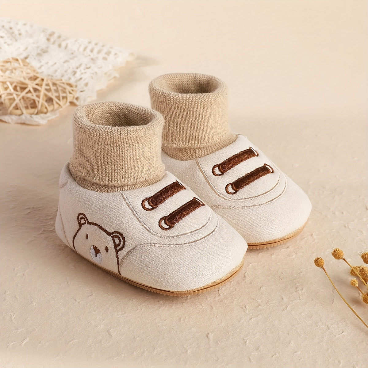 Beige baby sock booties with bear face and two brown lace-like stripes