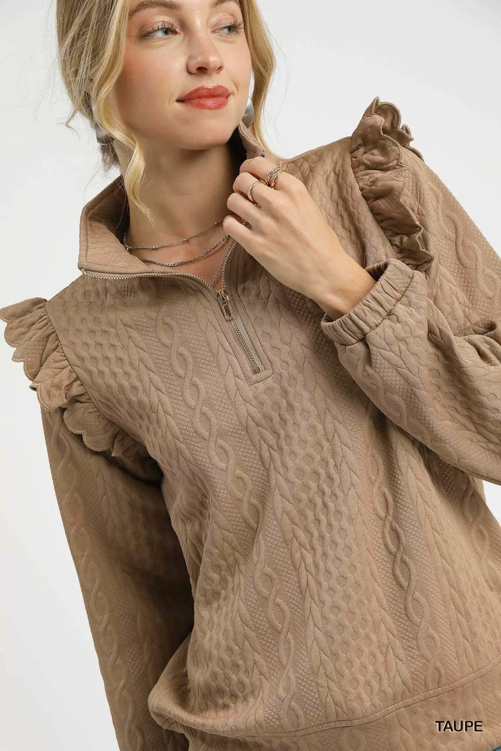 Close-up of taupe textured cable knit pullover with ruffle shoulders and half-zip