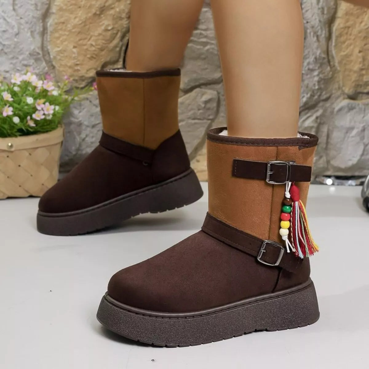 Brown ankle boots with buckled straps and multicolor tassel charm on the side.