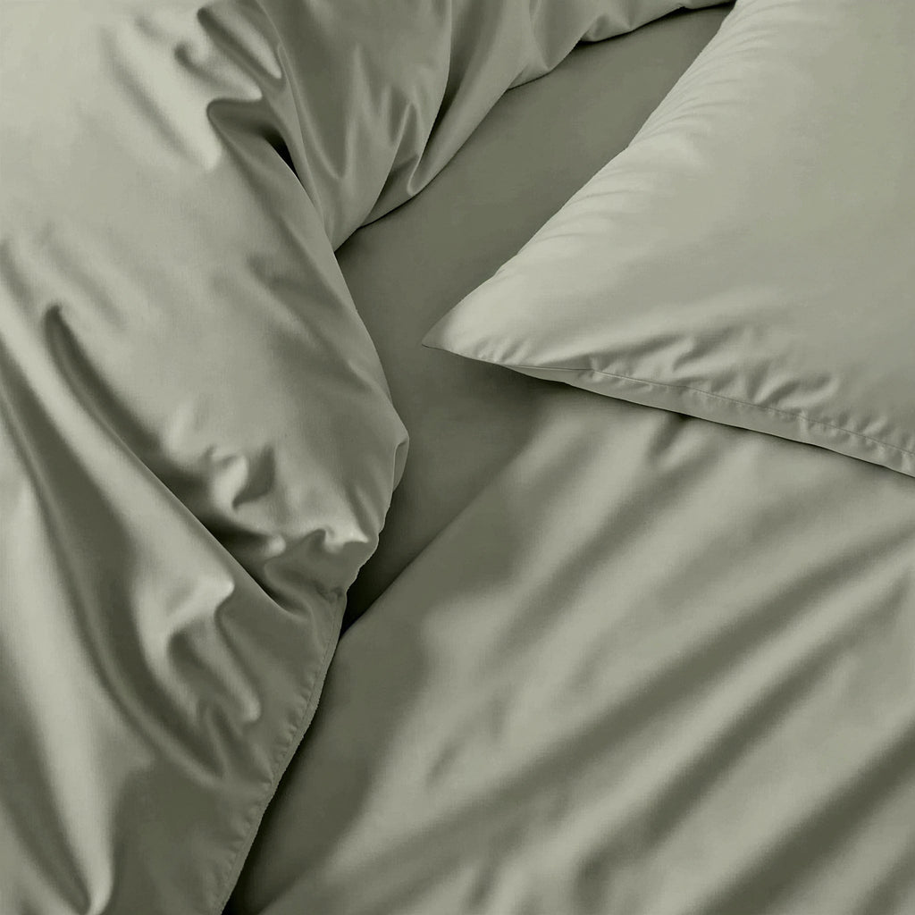 Sage green sateen duvet cover with smooth, slightly glossy fabric folds