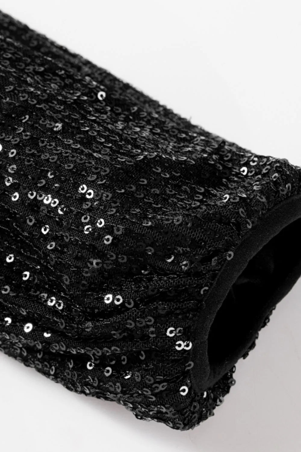 Black sequin long sleeve jacket sleeve close-up with glittering all-over texture