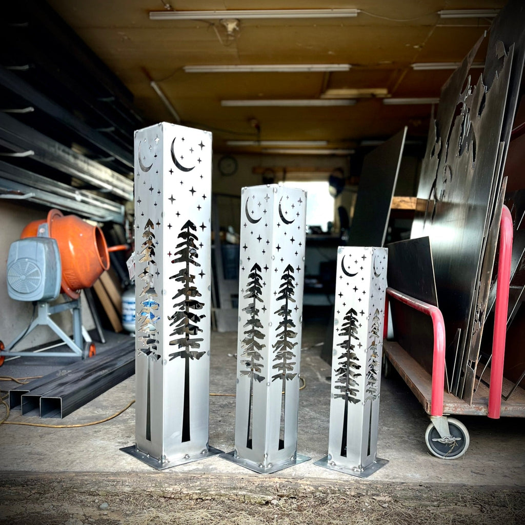 Set of silver steel solar light pillars showing star, moon, and pine tree cutouts.