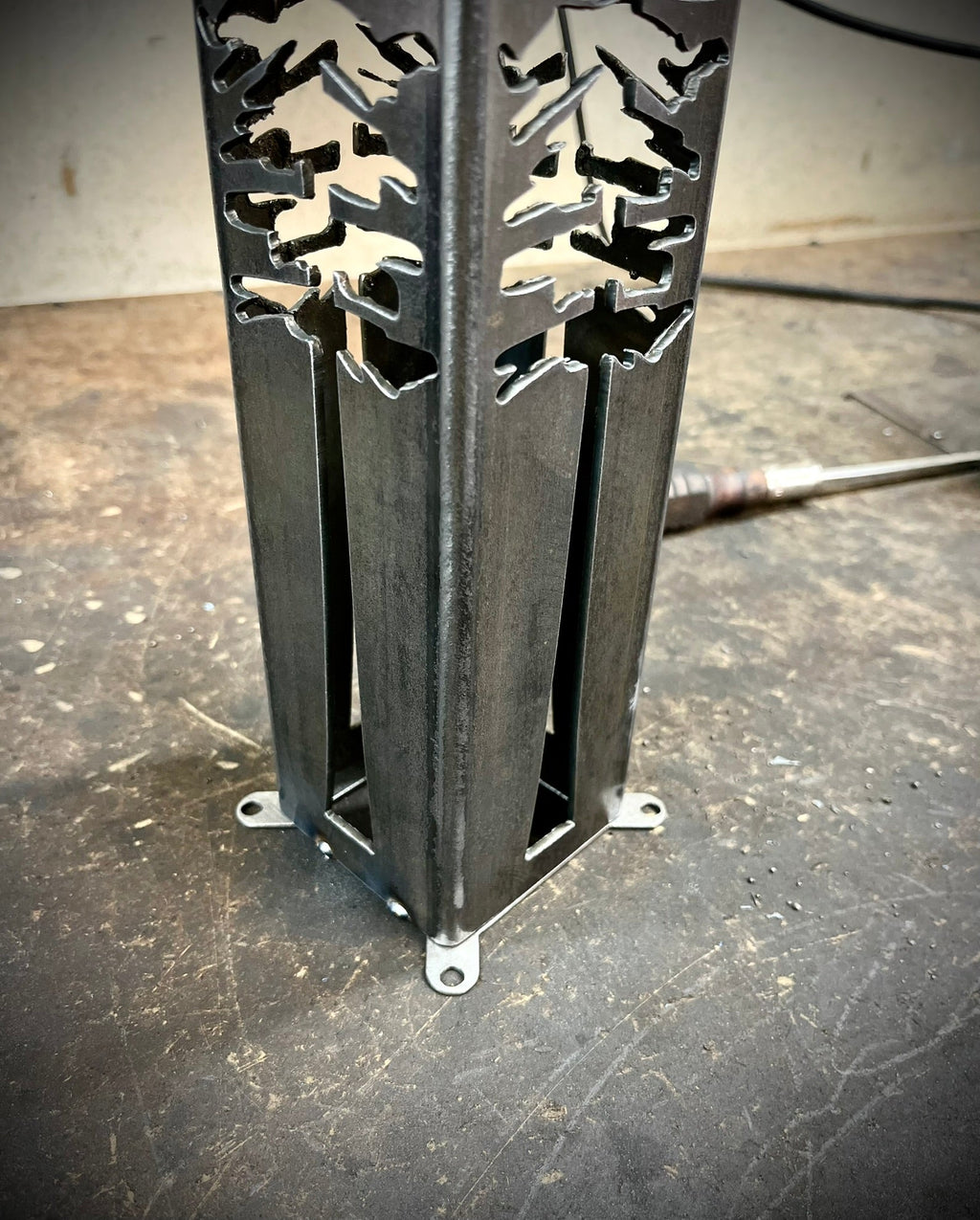 Dark steel solar pillar lantern with pine tree and star cutout panels and base