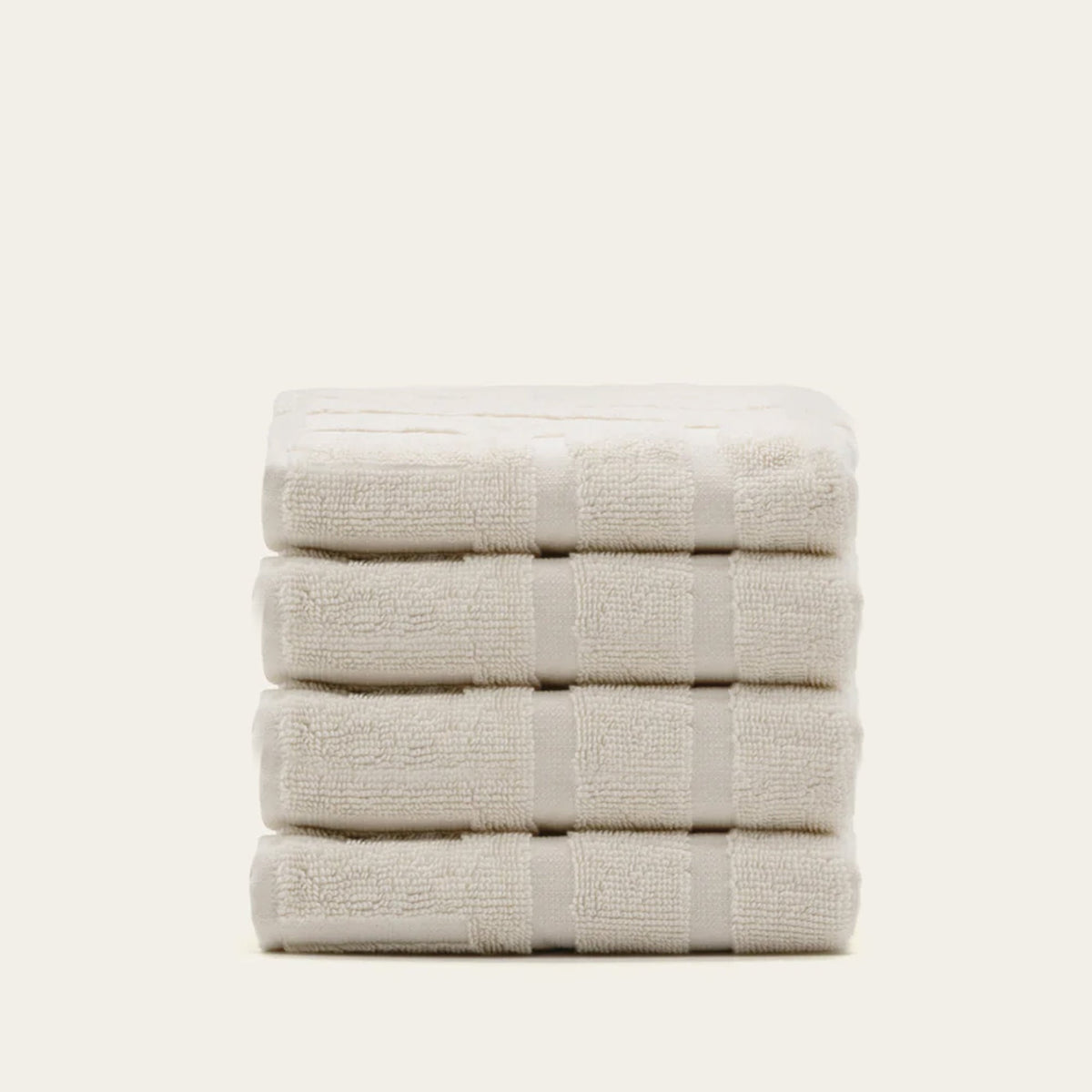 Ecru cotton towels folded in two stacks with subtle textured bands