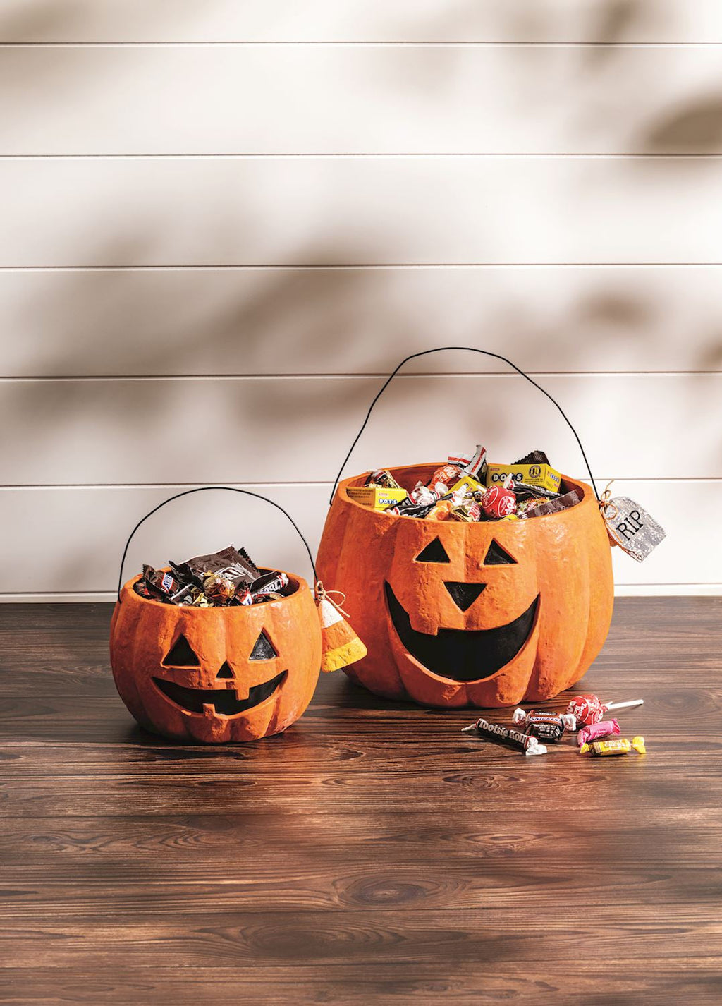 Small and large orange paper mache jack-o'-lantern treat buckets with smiling faces