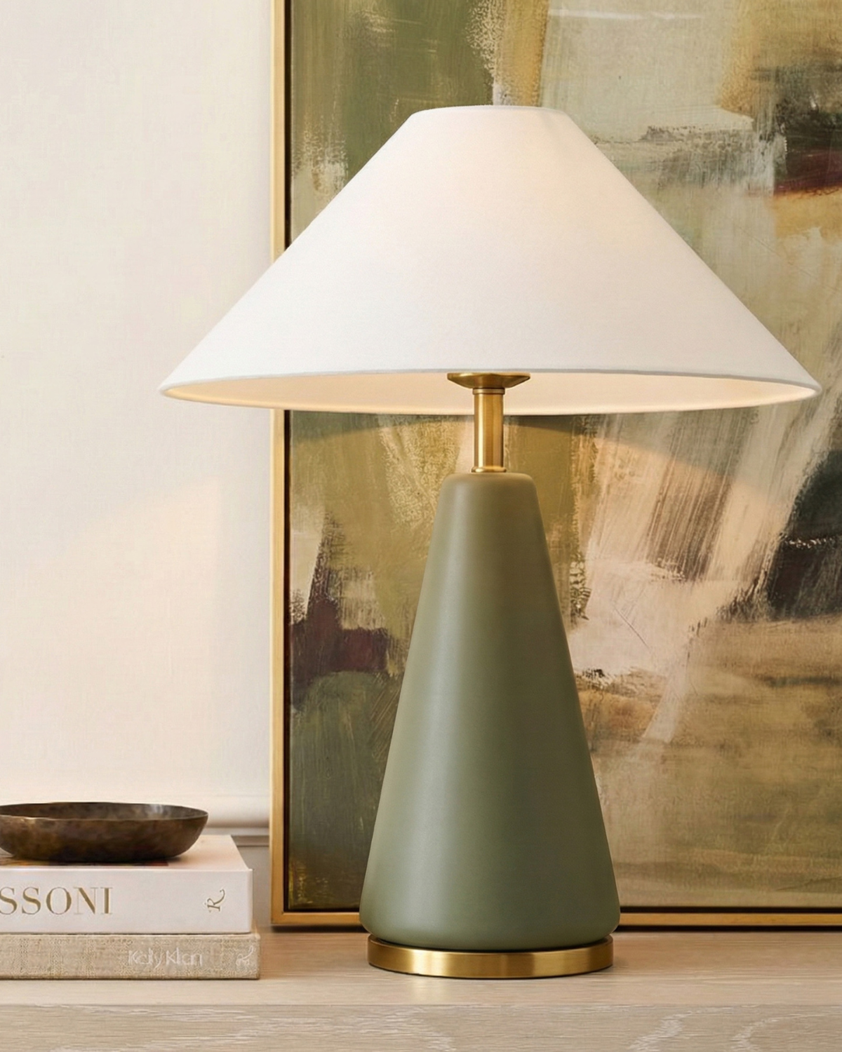 Olive green table lamp with white fabric shade and brass stem, on console table