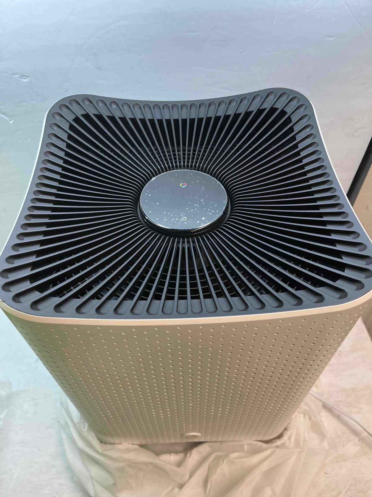 Air purifier front grille with circular fan area and dark control disc on top
