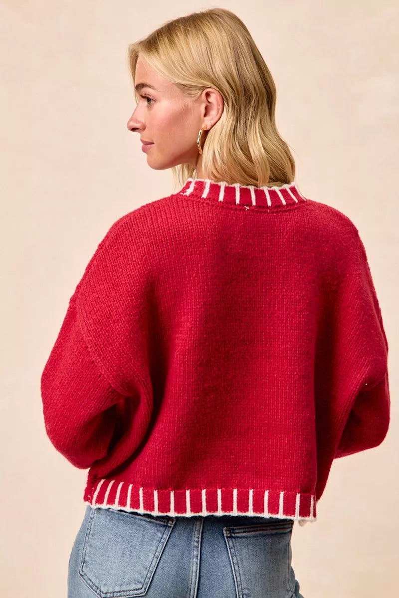 Red knit holiday sweater back view with white striped hem and wide sleeves