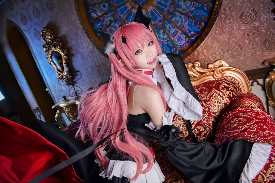 Black dress with white ruffled trim and red ribbon, horned headpiece beside ornate couch