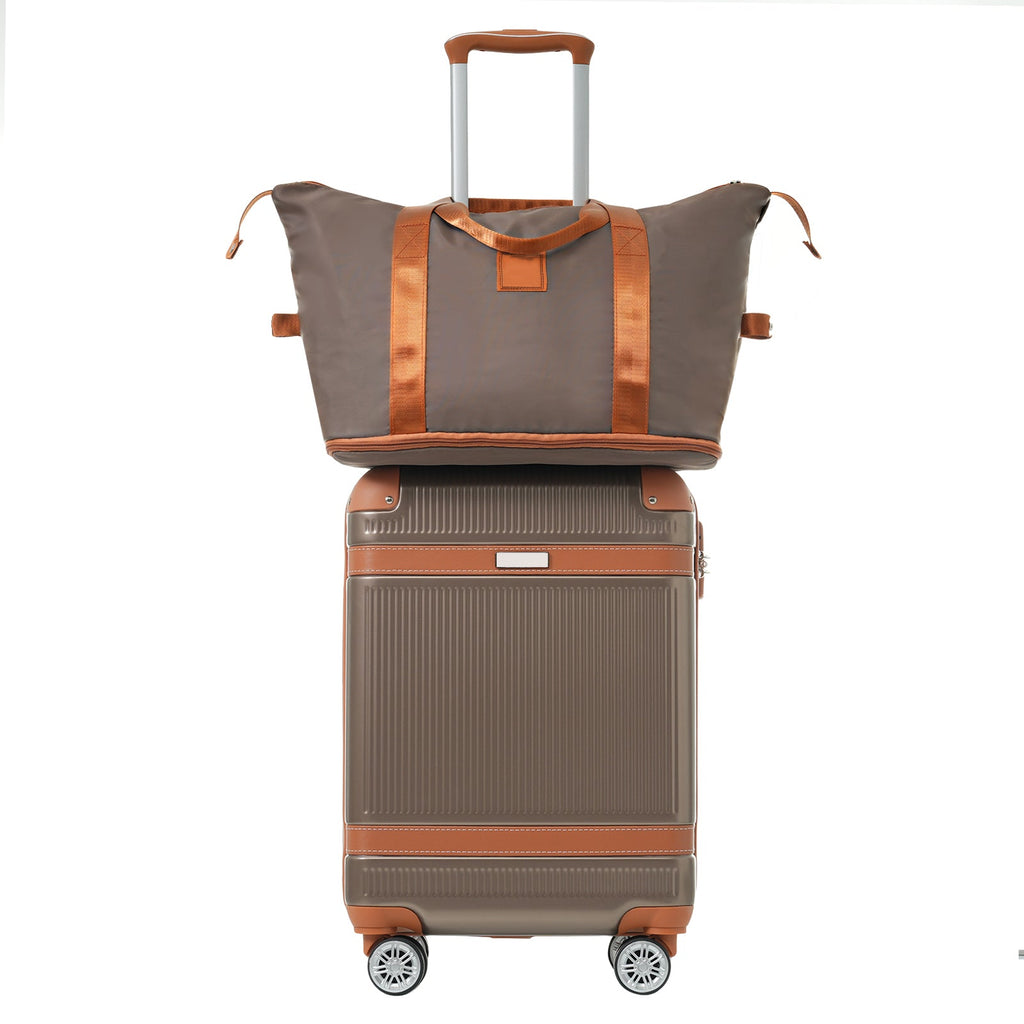 Copper-brown trim duffel bag stacked on a grey carry-on spinner suitcase