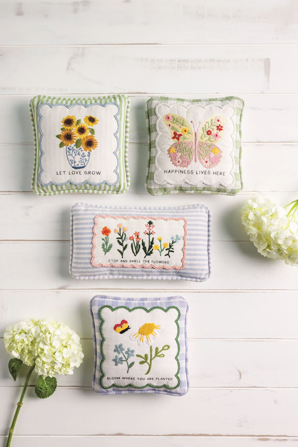 Set of four embroidered mini accent pillows with floral designs and embroidered sayings