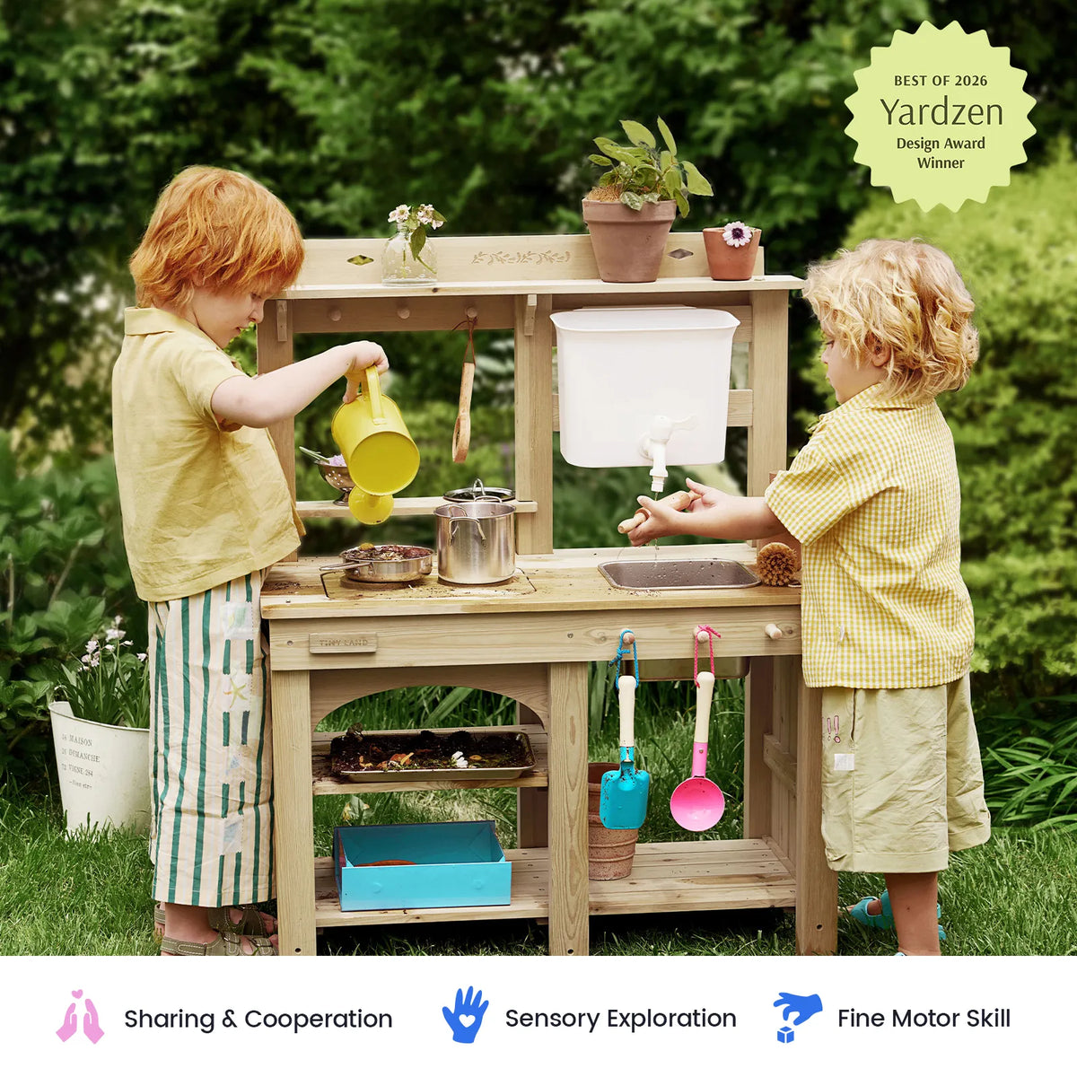 Two kids playing at wooden mud kitchen playset with water bin and utensil set
