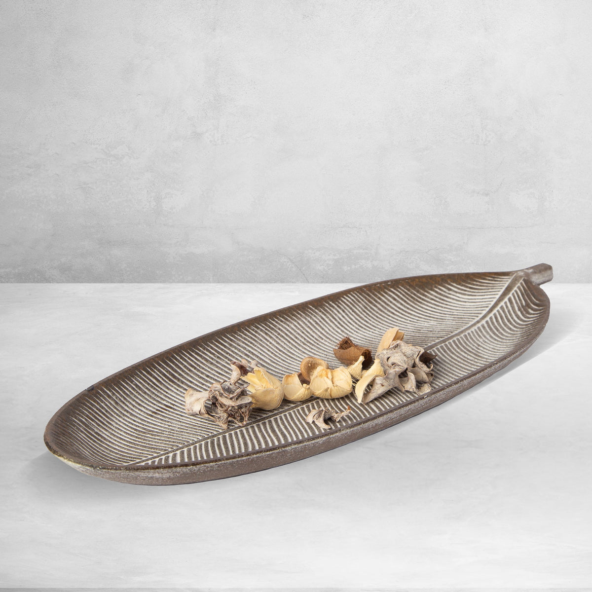 Dark brown leaf-shaped tray with raised ribbed lines and seashell display