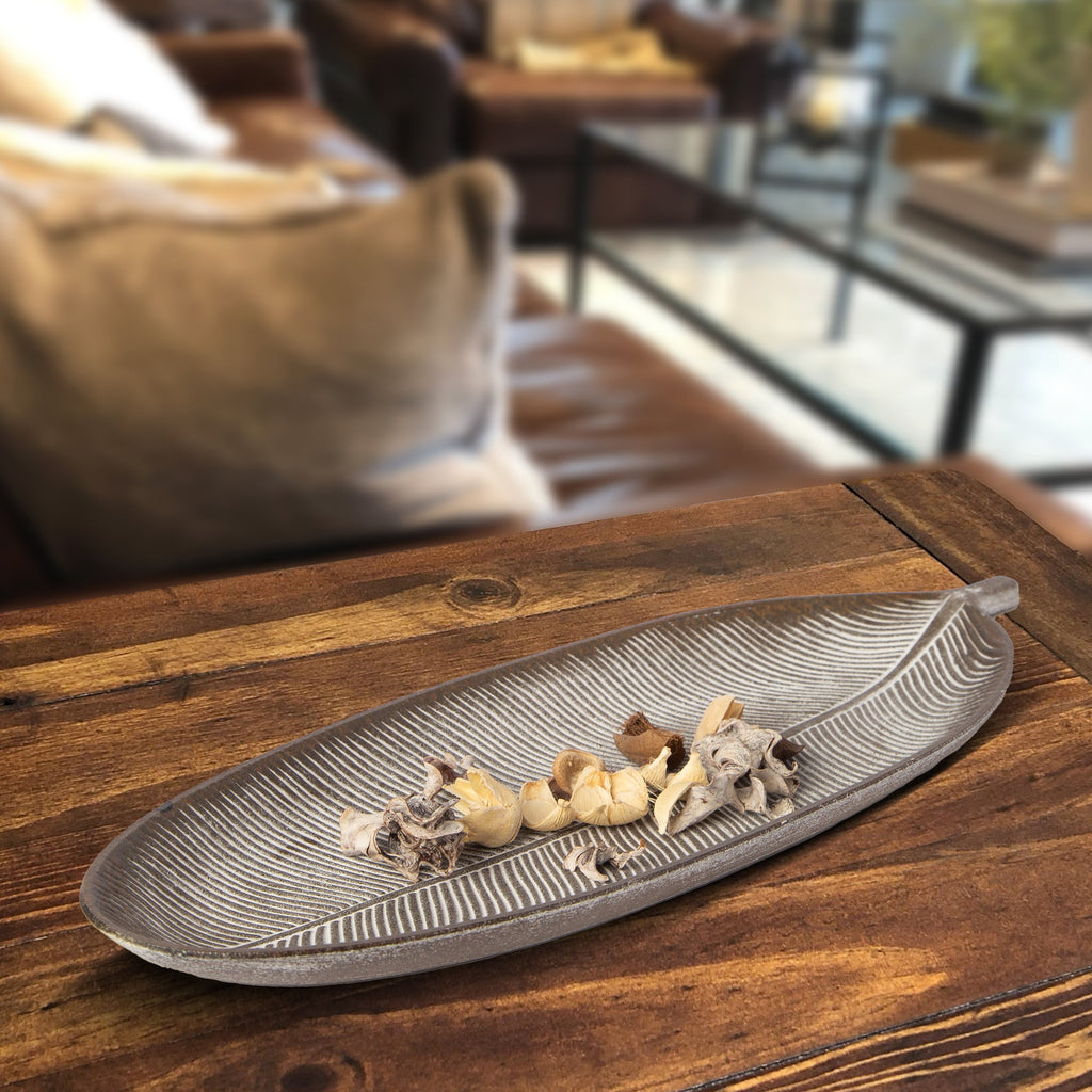Brown leaf-shaped MDF tray with white ribbed lines and dried decor on top