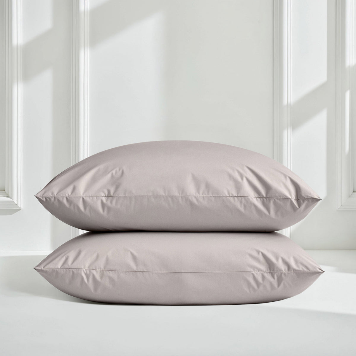 Light gray sateen pillow shams stacked on matching duvet