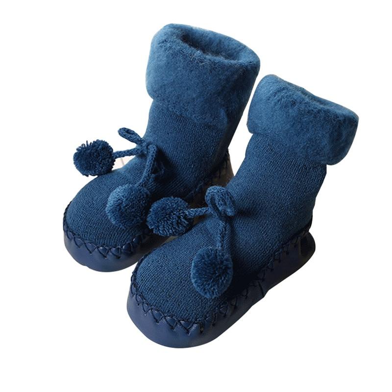 Pair of baby socks in navy blue with pom-pom ties and soft cuff loops