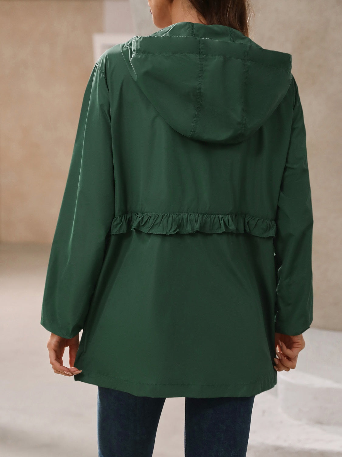 Women’s hooded windbreaker jacket back view, dark green with ruffle waist detail