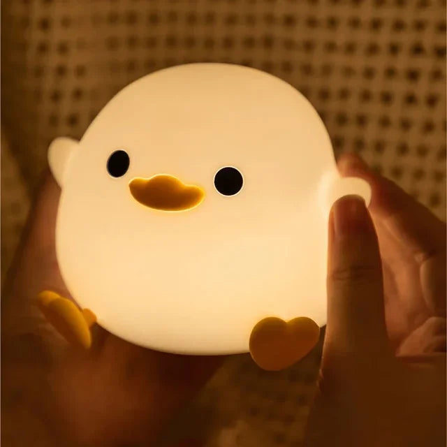 Duck silicone night light with warm glow, touched by a hand for control