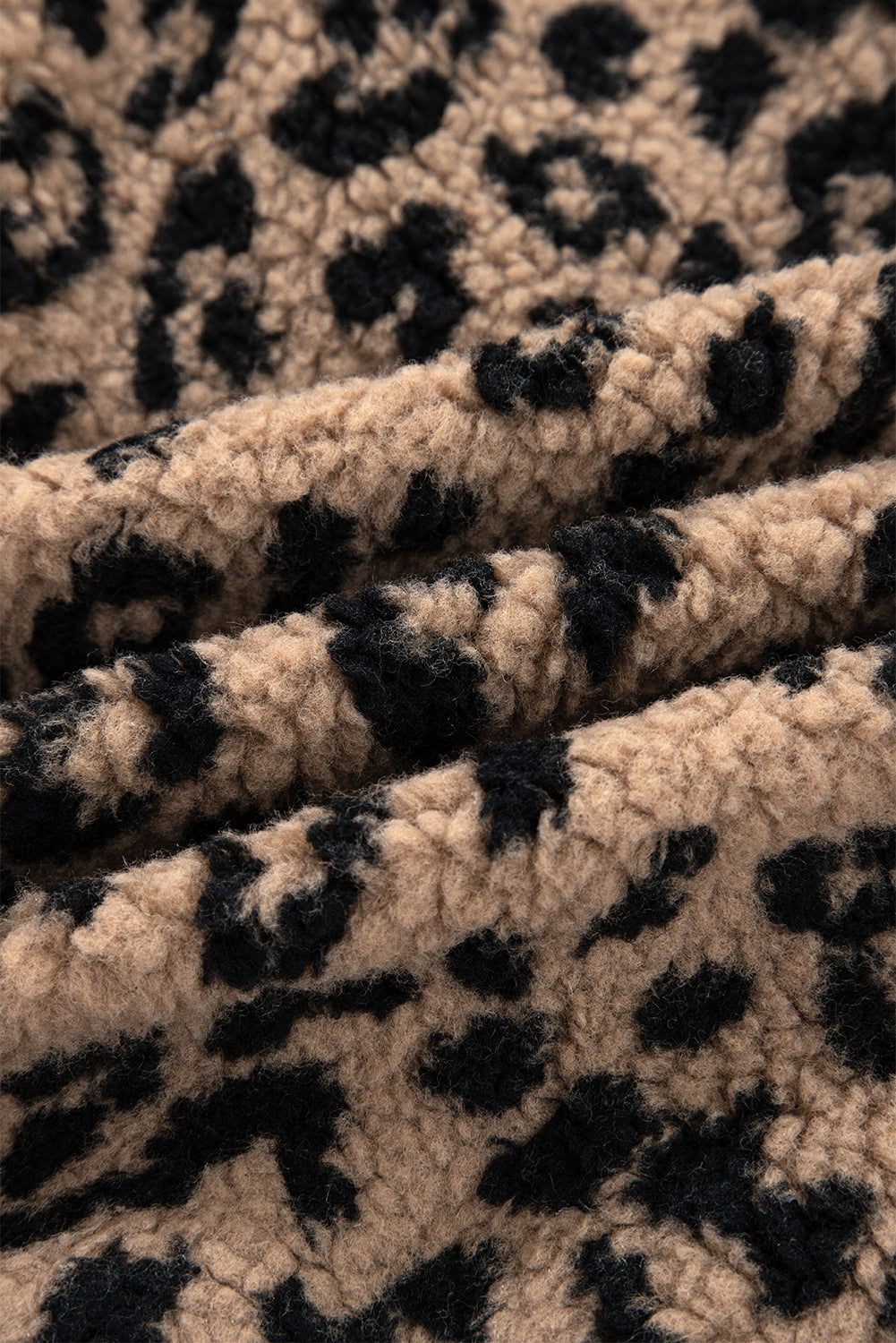 Leopard-print fleece fabric texture in khaki and black, soft fuzzy knit surface.