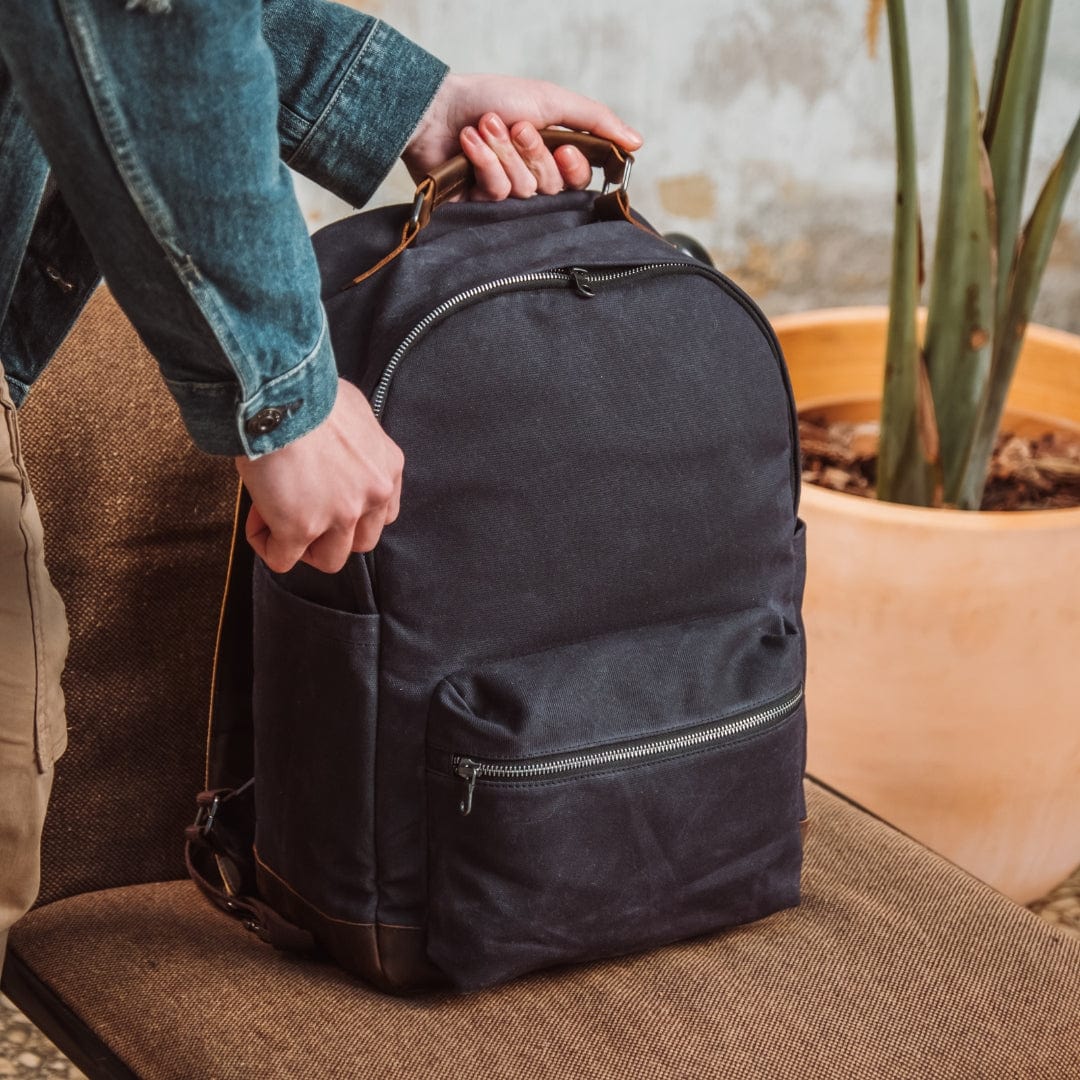 Dark navy backpack with top handle, front zip pocket, and side strap loops.