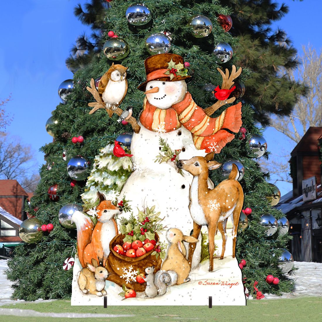 Christmas yard sign mounted against evergreen with snowman, deer, and woodland animals