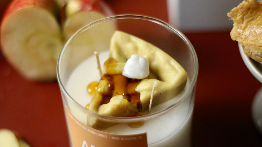 Apple pie container candle in clear glass jar with wax pastry, cream dollop, and syrup