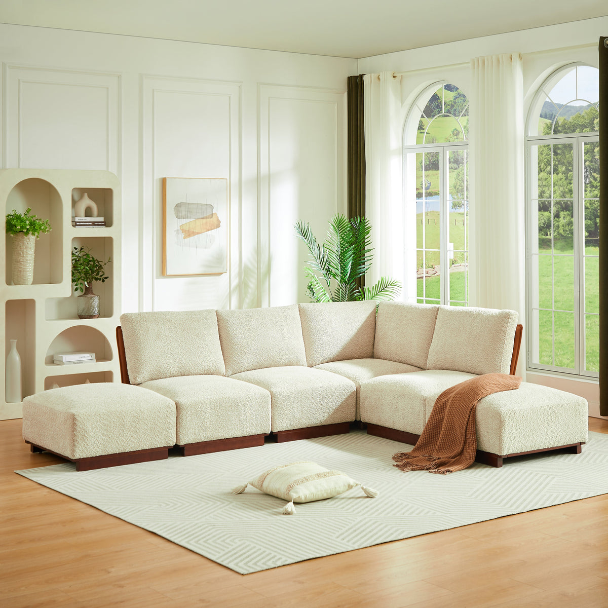 L-shaped boucle sectional sofa in light sesame with chaise and draped throw on ottoman