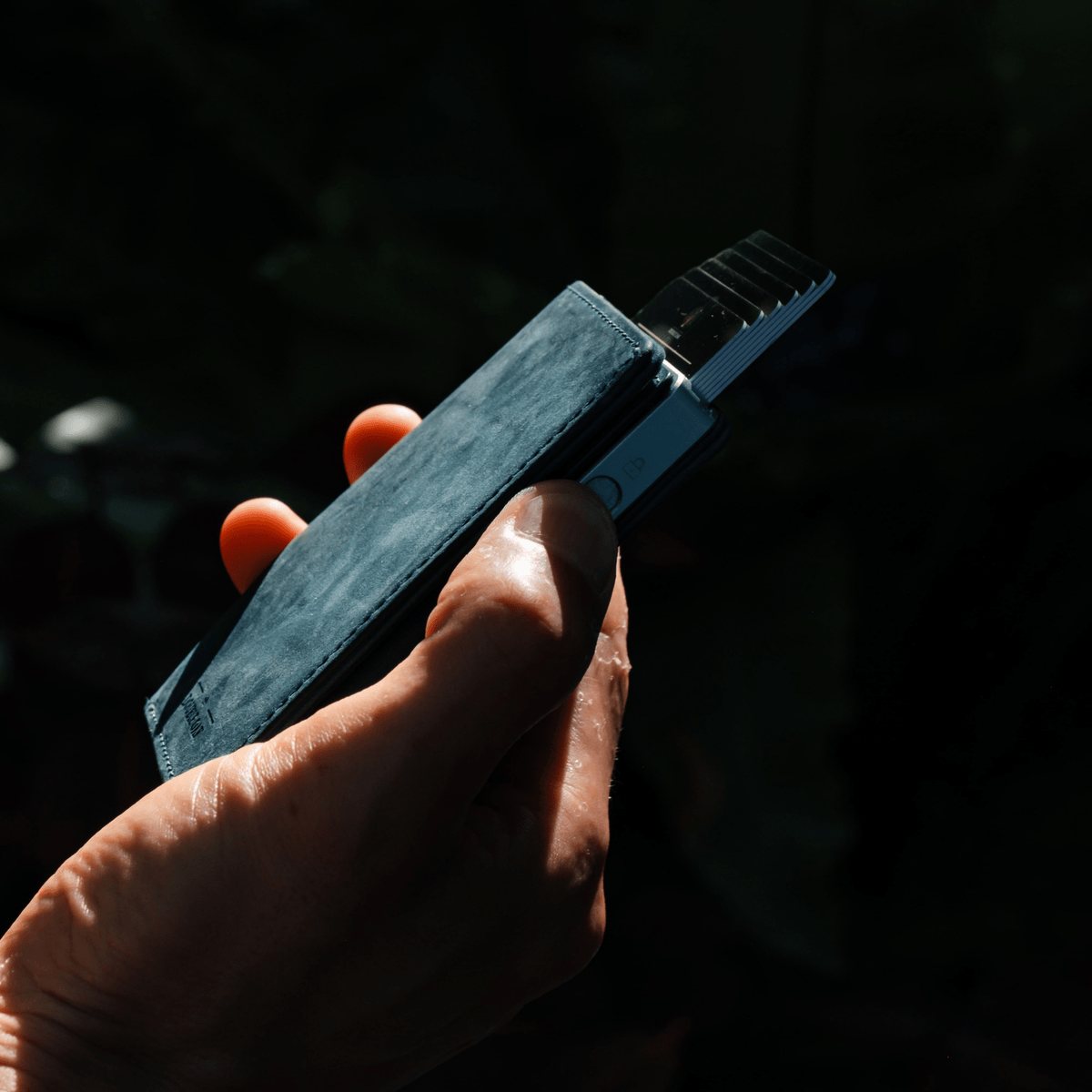 Blue leather bifold wallet with card slots and dark clasp, held close-up.