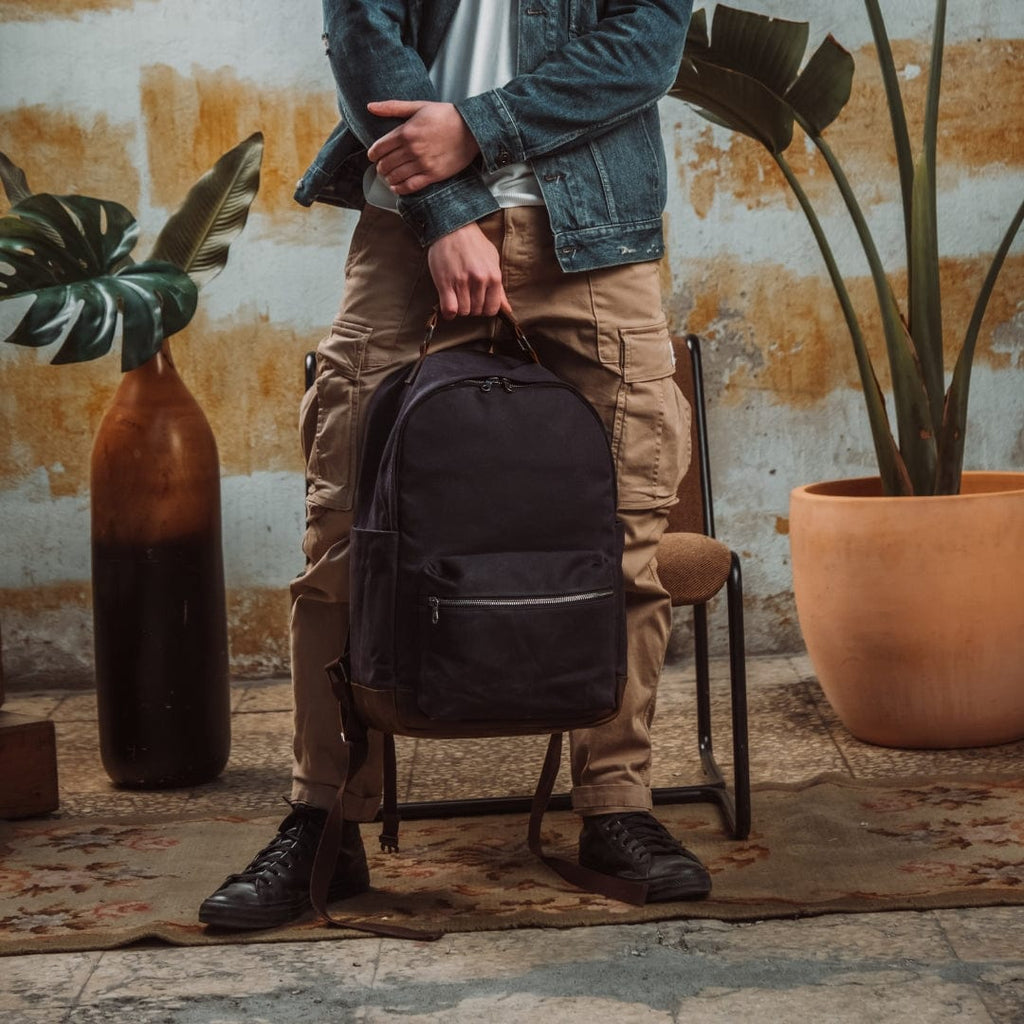 Backpack in dark color with front zip pocket and top handle straps