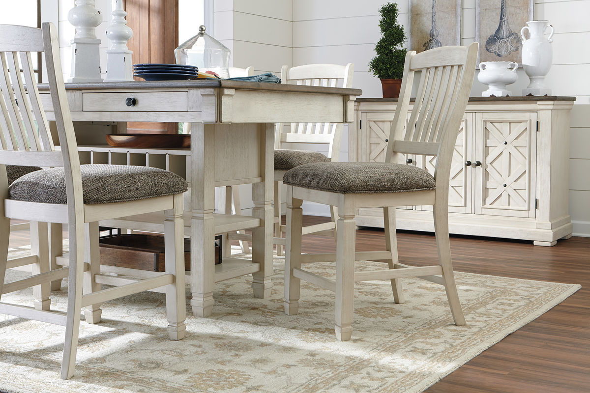 Beige counter table set with multiple cream chairs and server cabinet with doors and shelves.