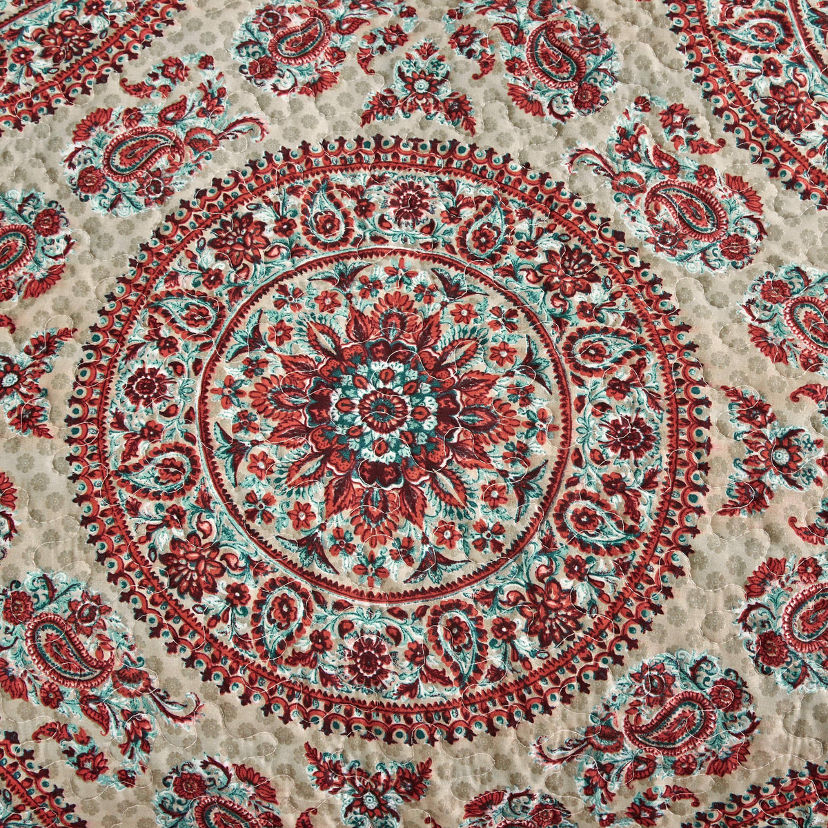 Fabric detail of centered medallion paisley in red and teal on off-white background