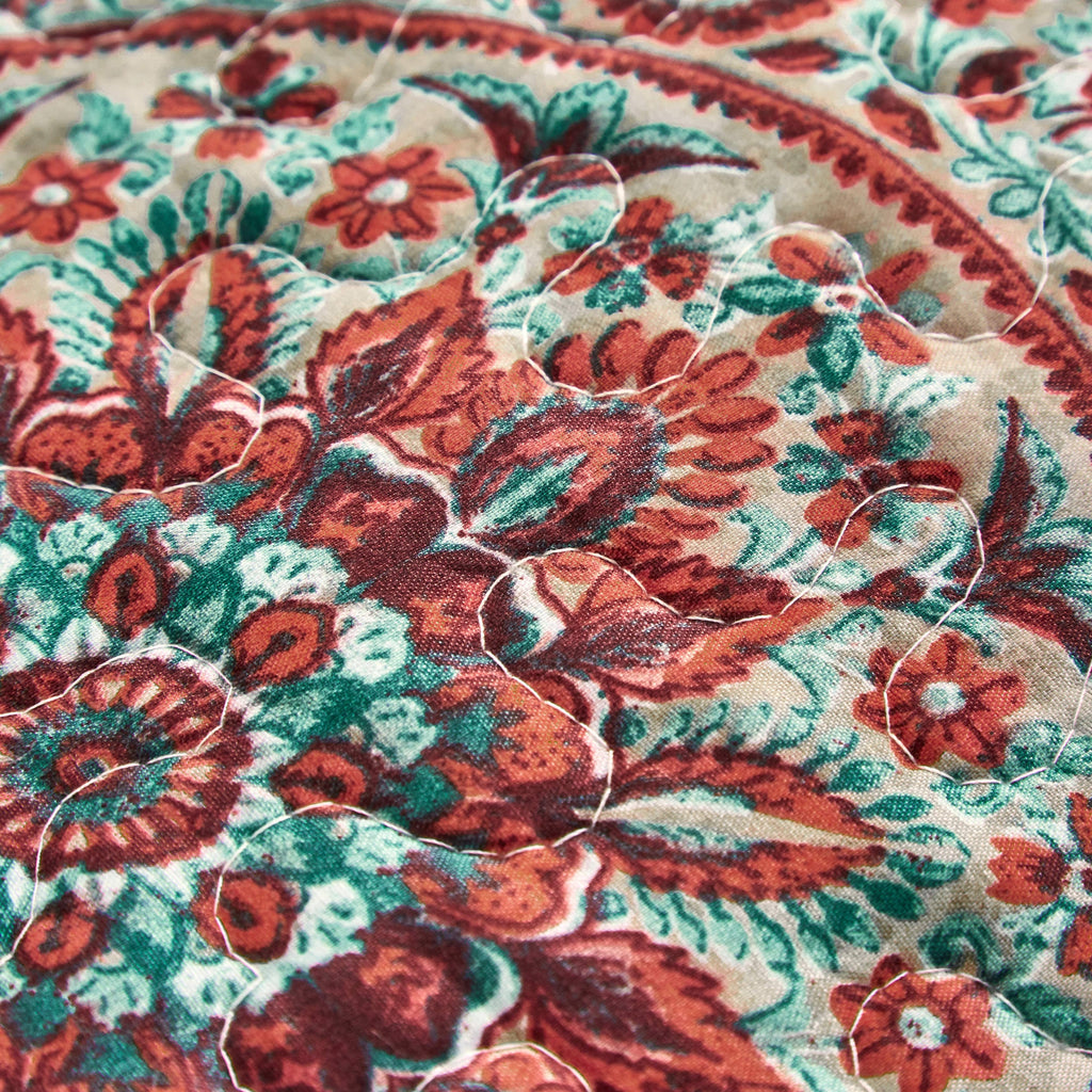 Close-up of boho paisley fabric: red, teal and rust florals on off-white