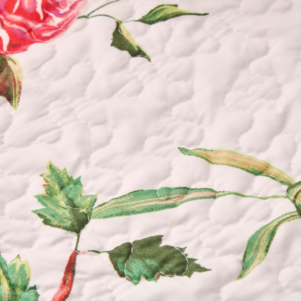 Close-up quilted dining table runner: white background with green vines and pink rose details
