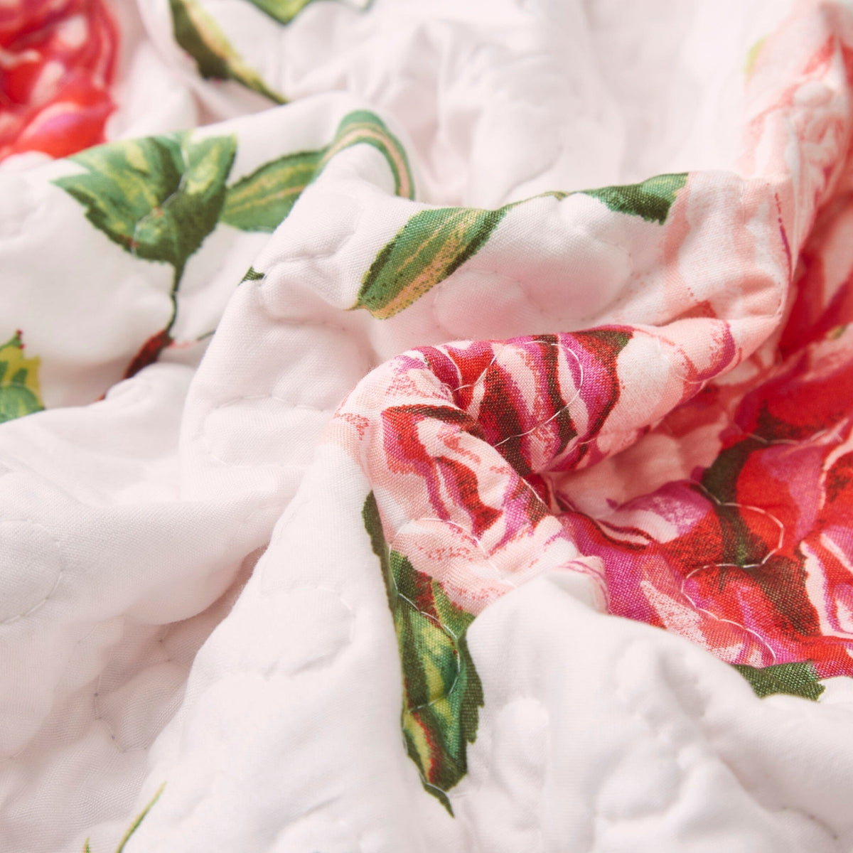 Close-up of quilted dining table runner texture with rose-and-leaf floral print on white