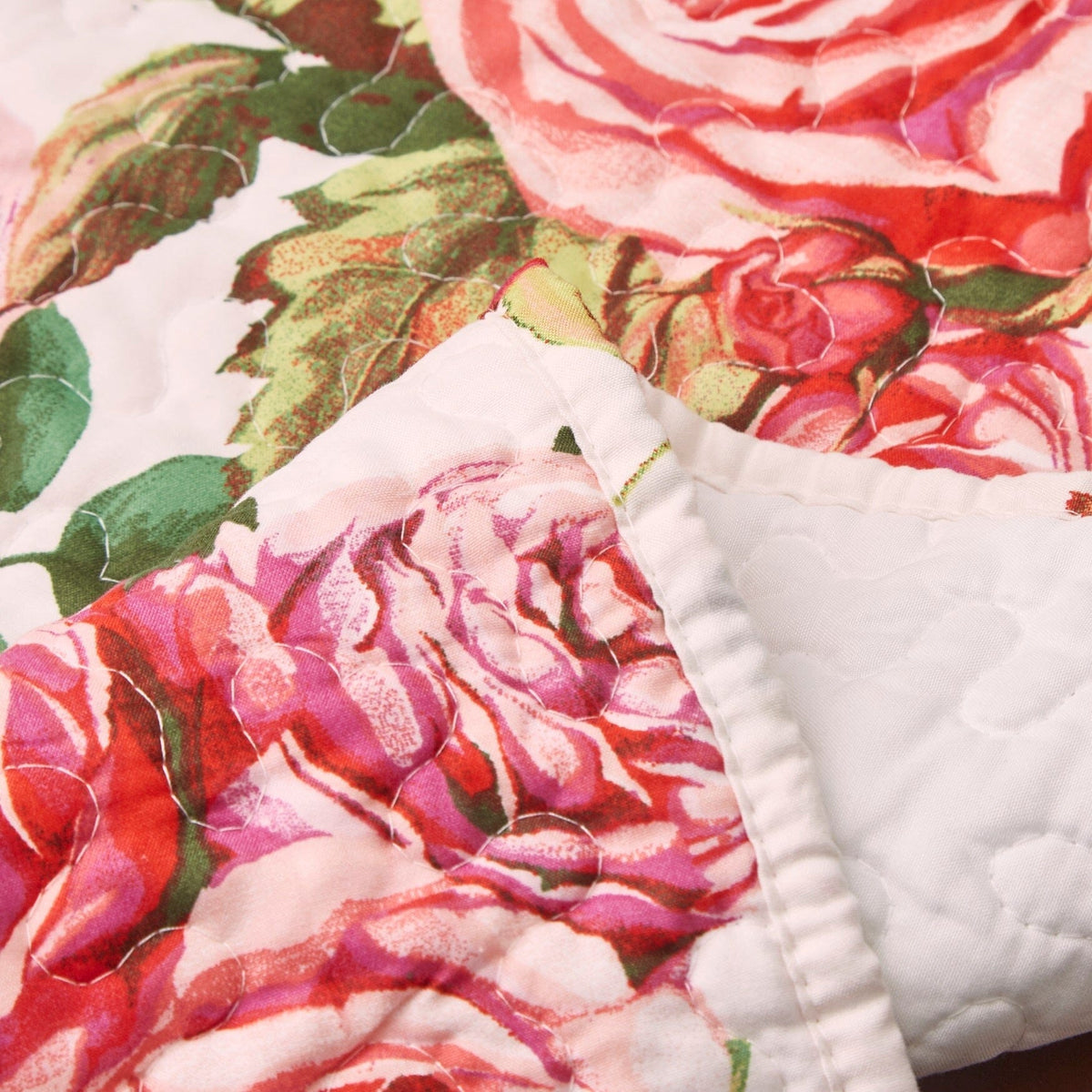 Close-up quilted dining table runner: white fabric with pink rose and green leaf print