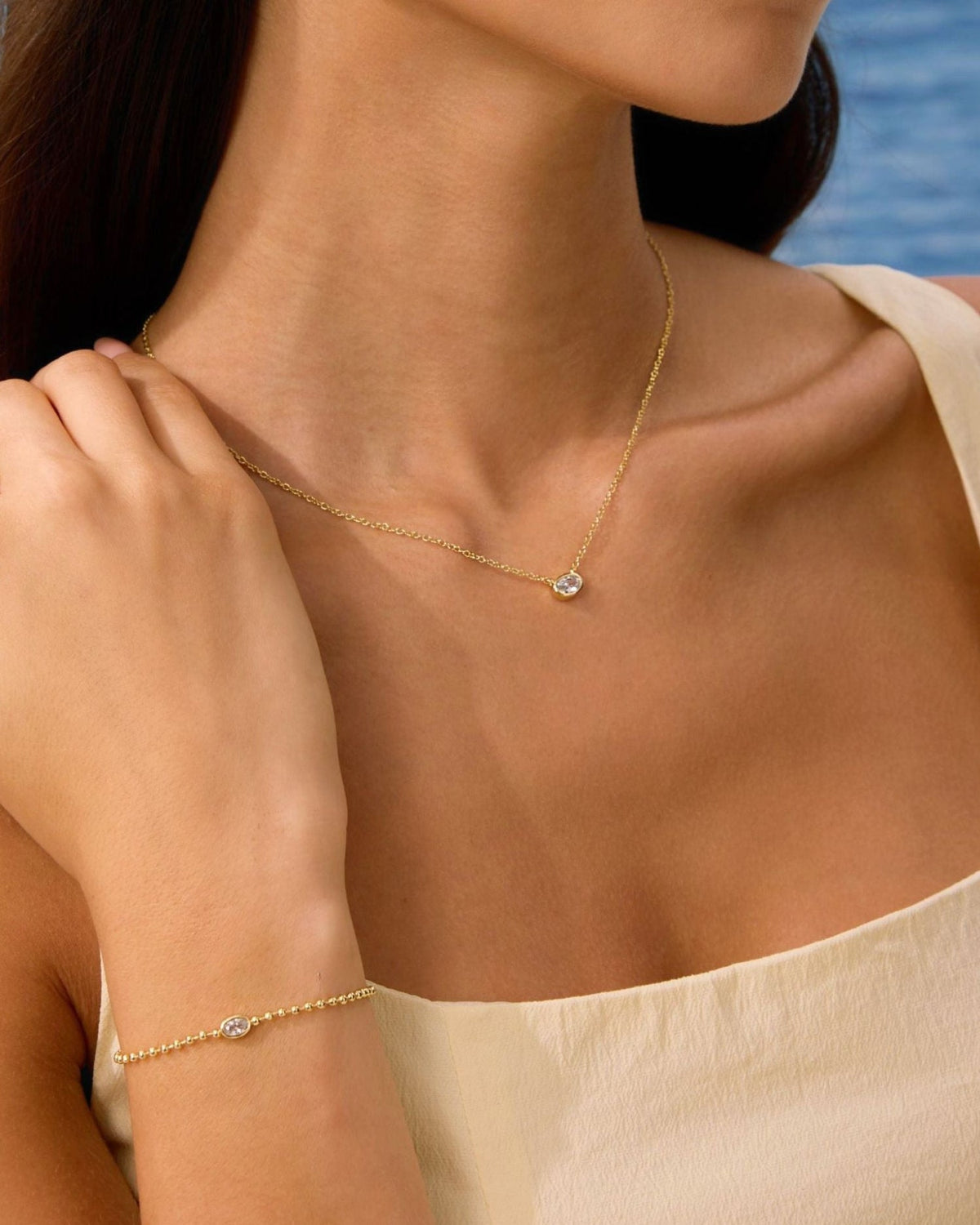 Gold oval diamond pendant necklace with thin chain; matching charm bracelet