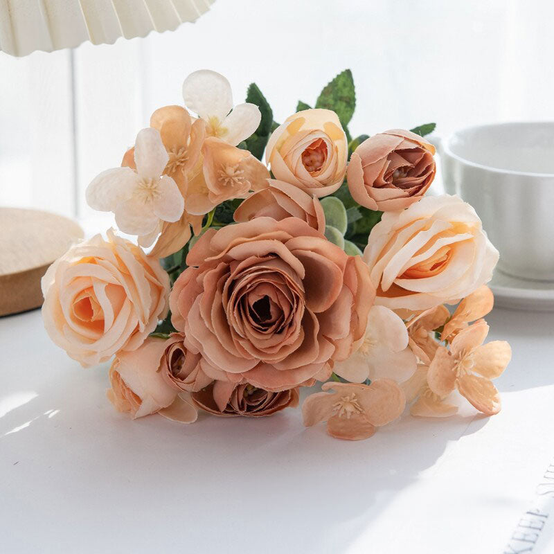 Peach and cream silk rose bouquet with green leaves in a clear vase