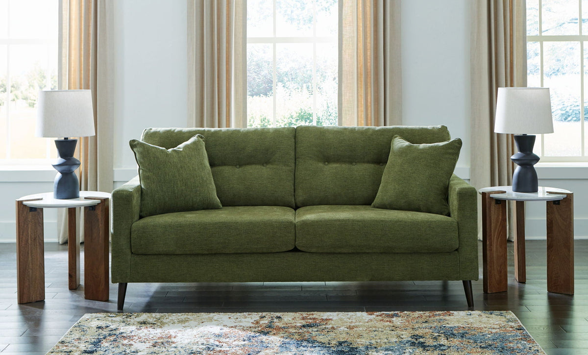 Green fabric sofa with plush cushions and tapered legs, styled in a living room