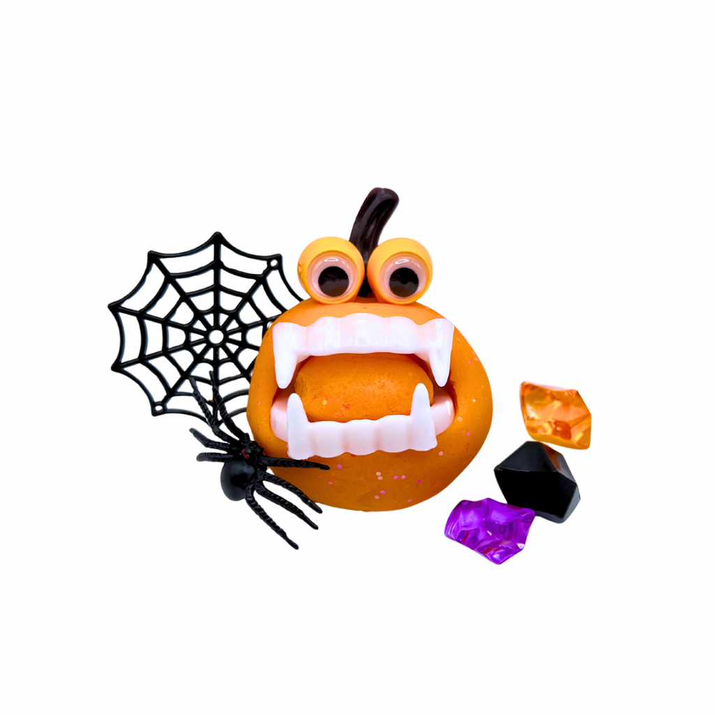 Pumpkin playdough jar with googly eyes and spider web, surrounded by colored sensory pieces