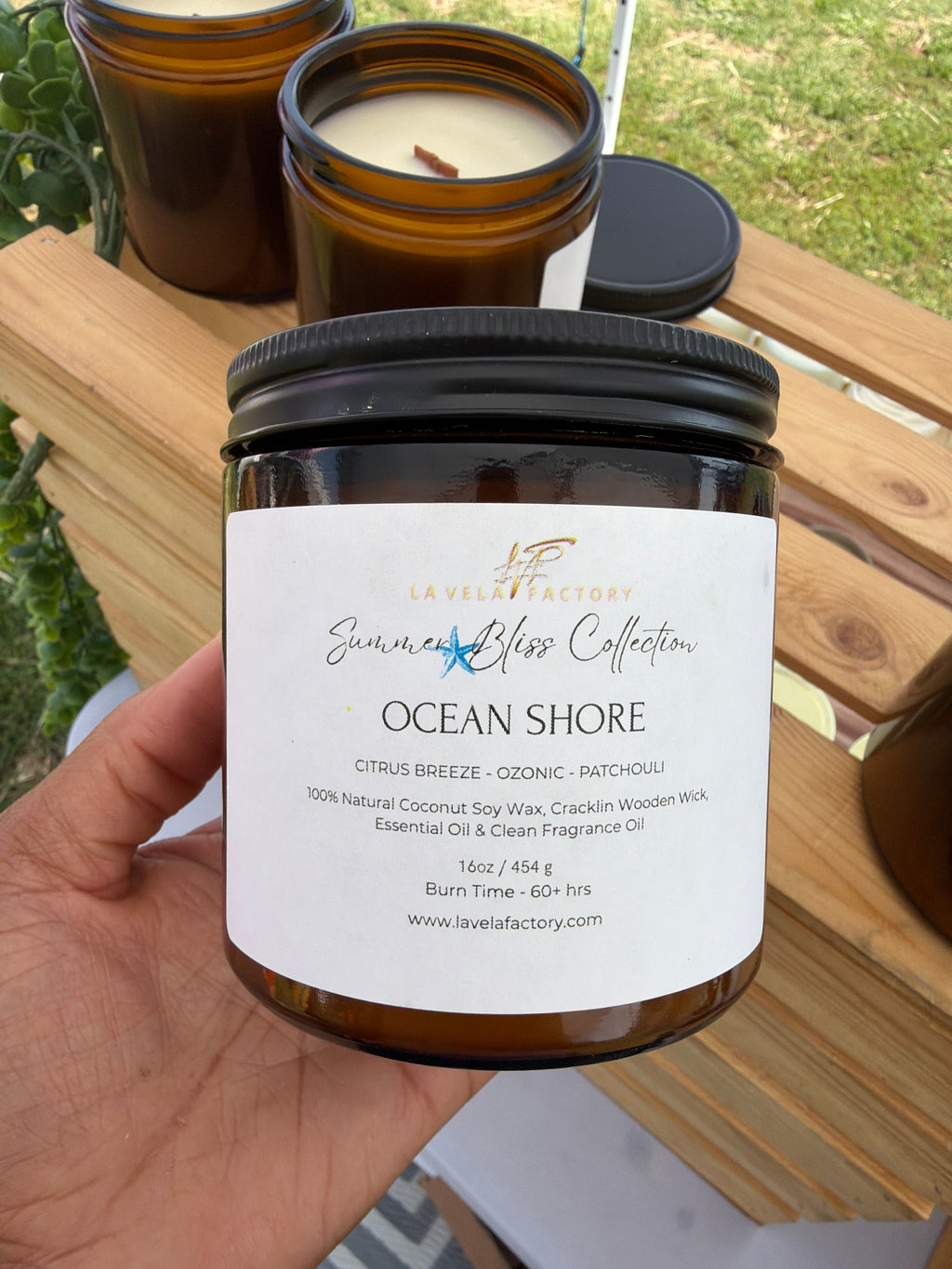 Amber glass jar candle with black lid, label for “Ocean Shore”