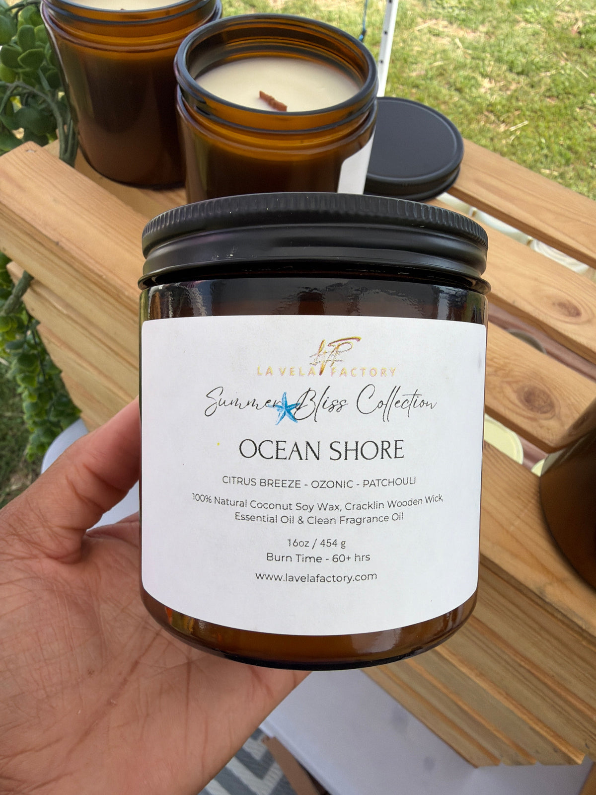 Amber glass jar candle with black lid, label for “Ocean Shore”