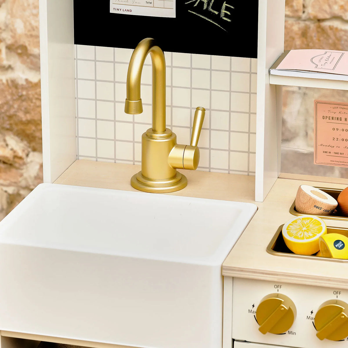 White play kitchen sink with gold faucet and side counter with accessories